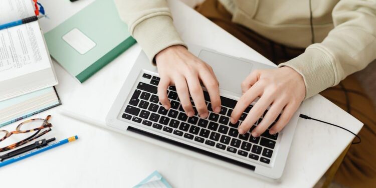 Free Person Typing on Laptop Studying at Desk Stock Photo